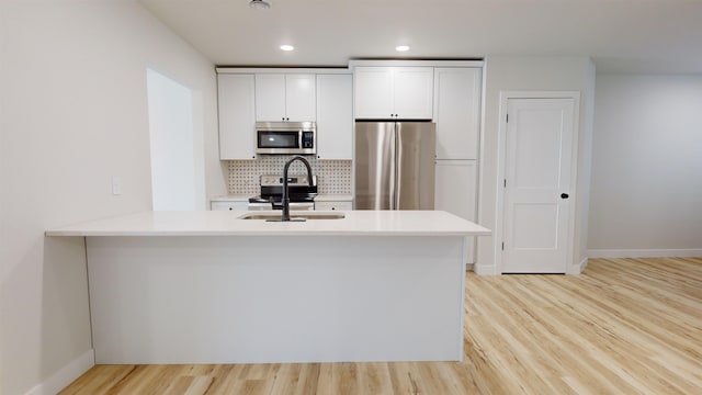 kitchen with sink, white cabinets, stainless steel appliances, and light hardwood / wood-style floors