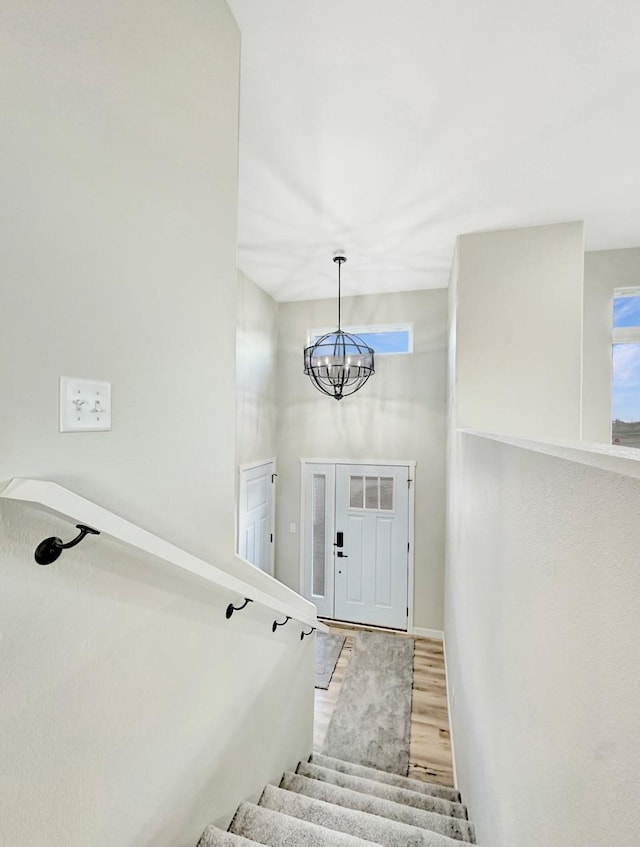 staircase with a chandelier and wood finished floors