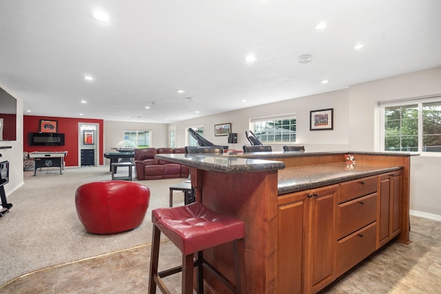 kitchen featuring a breakfast bar, a healthy amount of sunlight, a kitchen island, and light carpet