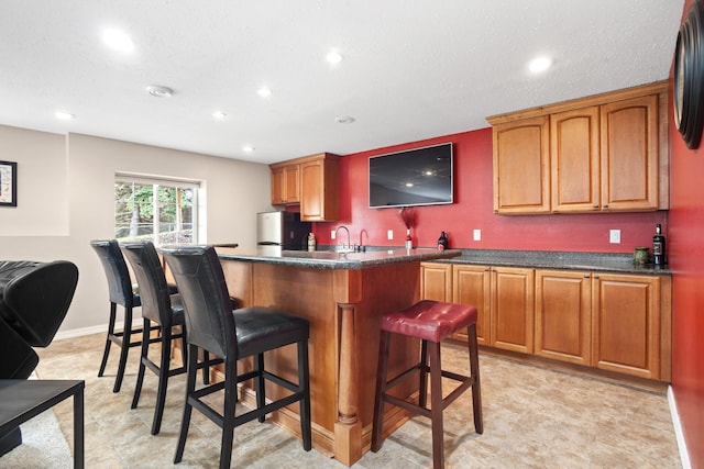 kitchen with sink, stainless steel refrigerator, and a breakfast bar area