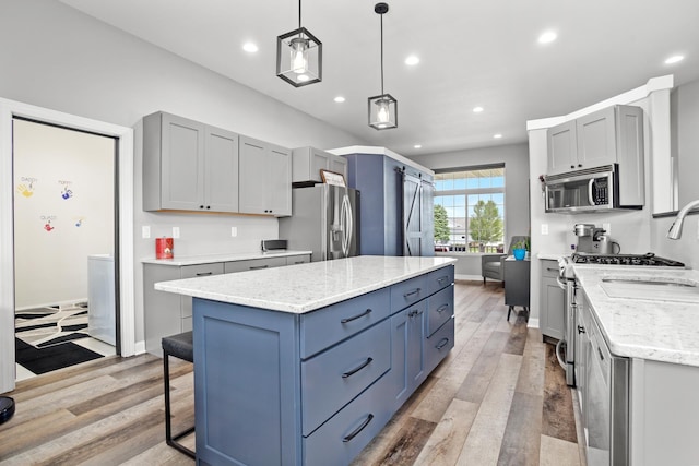 kitchen with decorative light fixtures, a kitchen island, light stone counters, and stainless steel appliances