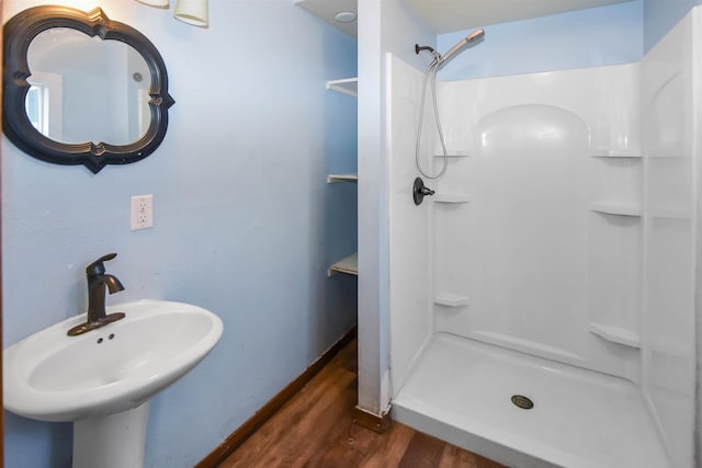 bathroom featuring hardwood / wood-style flooring, a shower, and sink