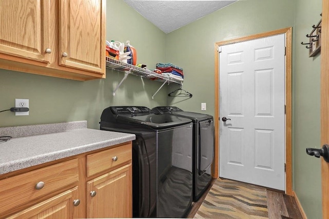 washroom with a textured ceiling, separate washer and dryer, cabinets, and dark wood-type flooring