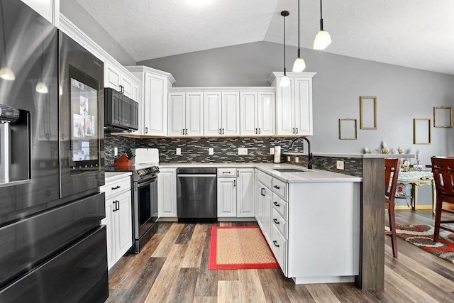 kitchen with sink, stainless steel appliances, white cabinetry, and lofted ceiling