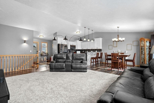 living room with lofted ceiling, a chandelier, and dark wood-type flooring