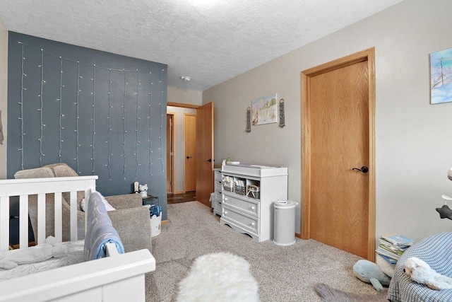 carpeted bedroom with a nursery area and a textured ceiling