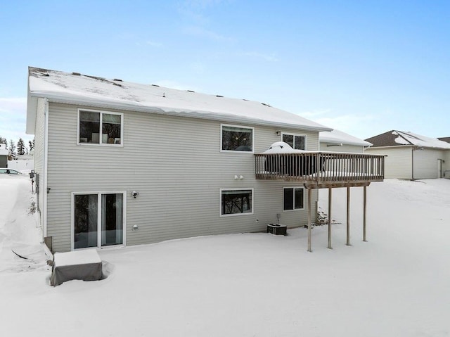 snow covered property featuring central air condition unit and a wooden deck