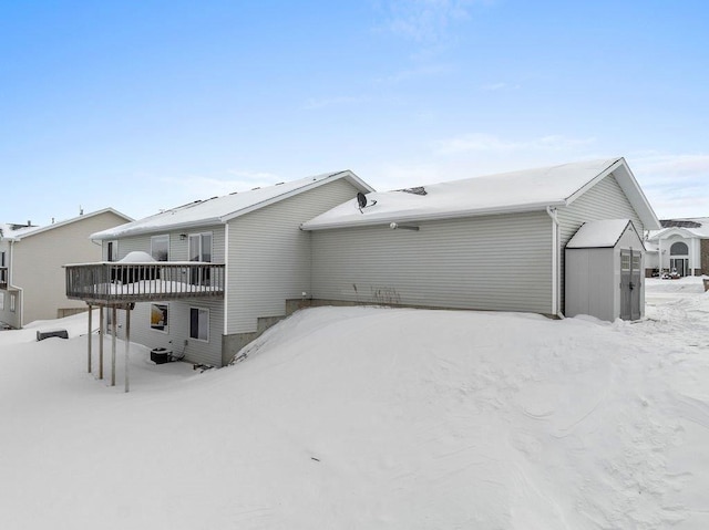 snow covered back of property with a deck