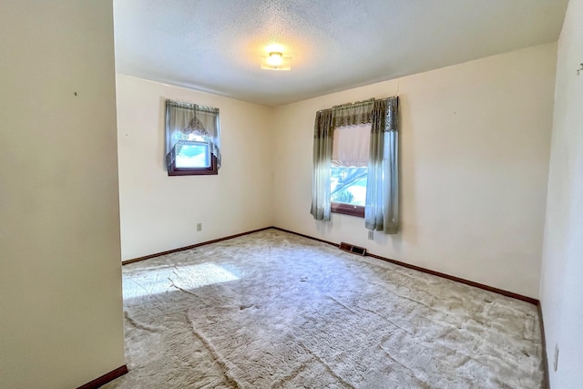 carpeted empty room with a textured ceiling