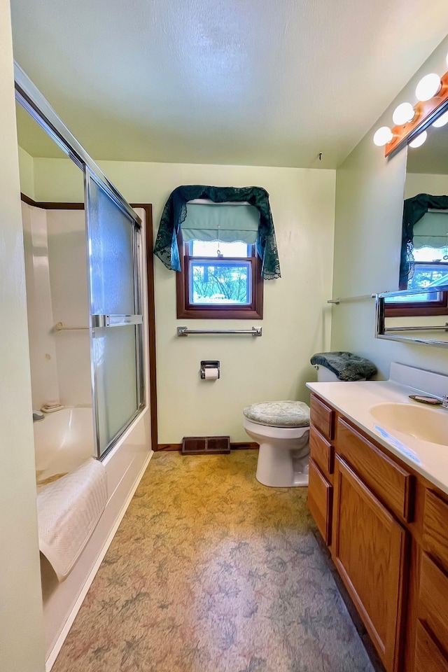 full bathroom featuring combined bath / shower with glass door, vanity, and toilet