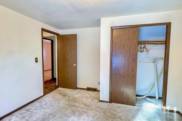 unfurnished bedroom featuring light carpet, a textured ceiling, and a closet