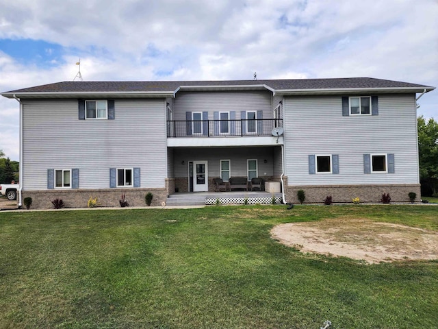 back of house with brick siding, a lawn, and a balcony