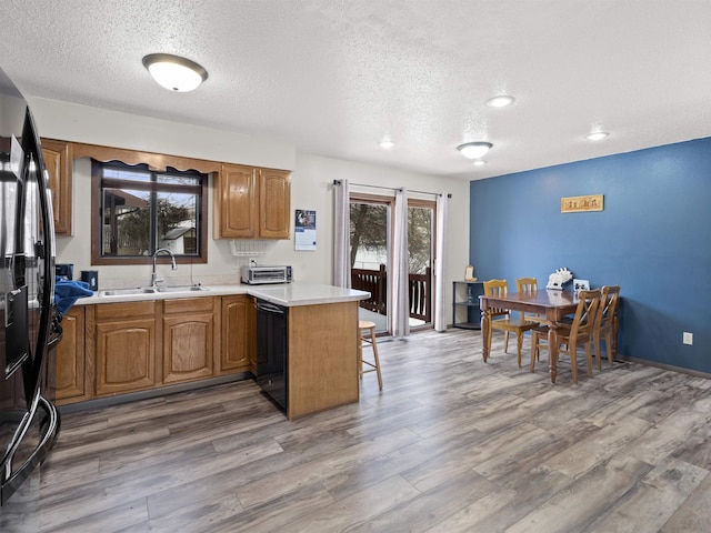 kitchen with kitchen peninsula, a kitchen breakfast bar, a textured ceiling, black appliances, and sink