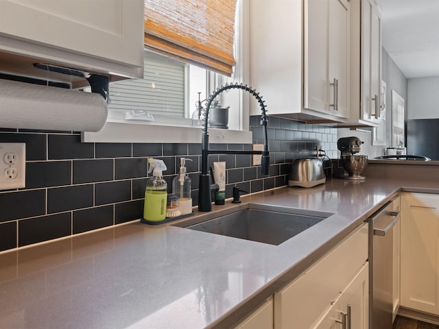 kitchen with white cabinets, decorative backsplash, and sink