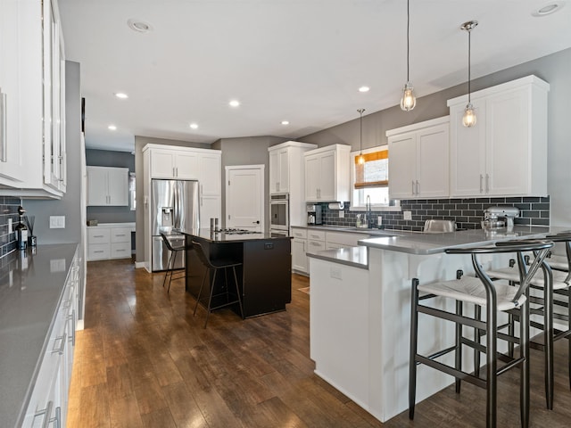 kitchen with decorative light fixtures, a center island, stainless steel refrigerator with ice dispenser, white cabinetry, and a kitchen breakfast bar