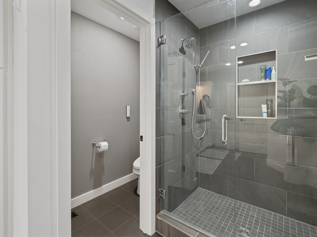 bathroom with toilet, tile patterned flooring, and a shower with door