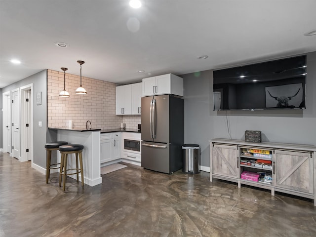 kitchen with a kitchen breakfast bar, white cabinetry, stainless steel fridge, and hanging light fixtures