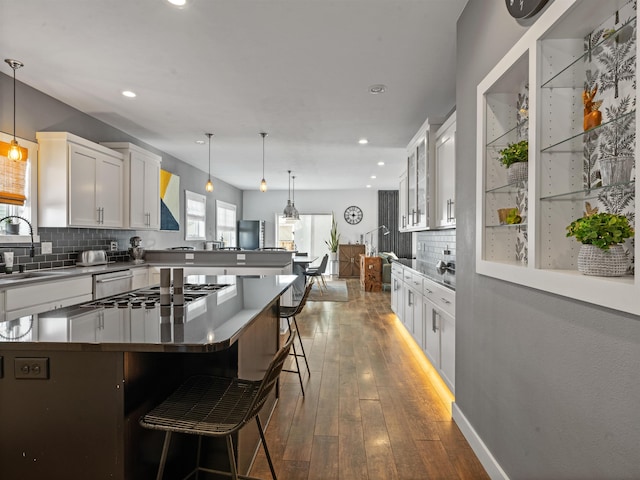 kitchen featuring a kitchen bar, stainless steel appliances, backsplash, white cabinets, and sink