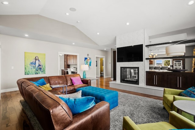 living room featuring light wood-type flooring, vaulted ceiling, and a fireplace