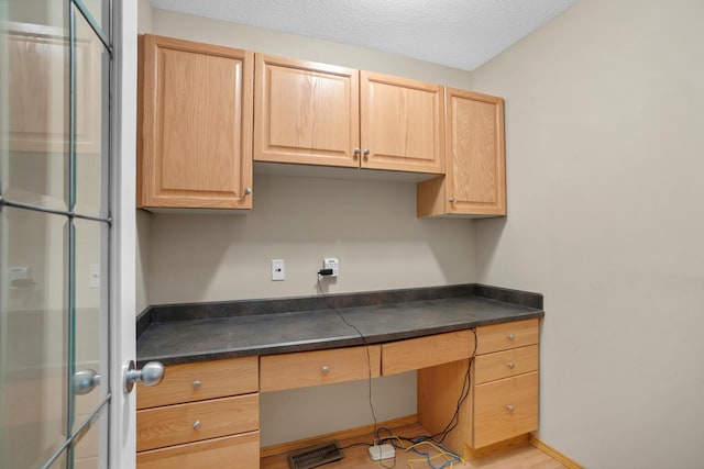 529 Rice Lake Rd, Rice Lake, ND 58735 - kitchen featuring light brown cabinetry, a textured ceiling, and built in desk