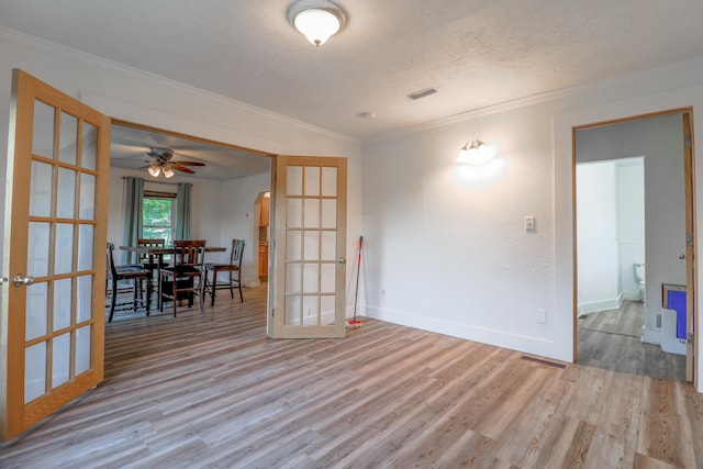 spare room featuring light hardwood / wood-style flooring, french doors, crown molding, and a textured ceiling