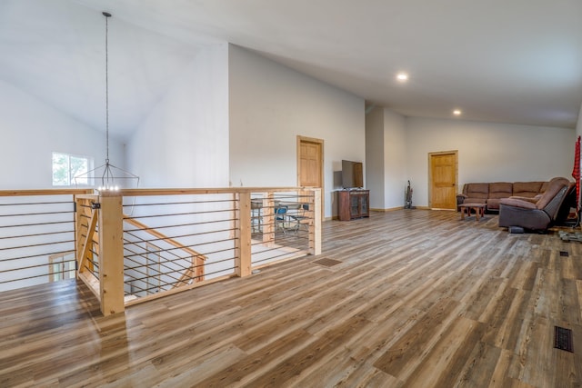 living room featuring high vaulted ceiling, hardwood / wood-style floors, and a chandelier