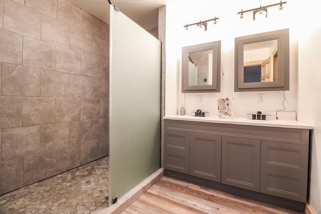 bathroom with hardwood / wood-style flooring, tiled shower, and vanity