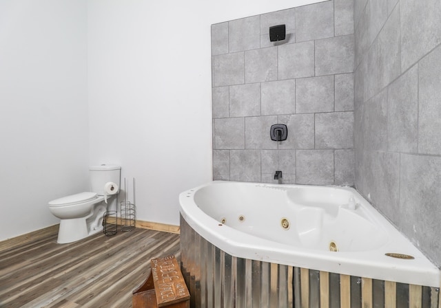 bathroom with hardwood / wood-style flooring, toilet, and a tub to relax in