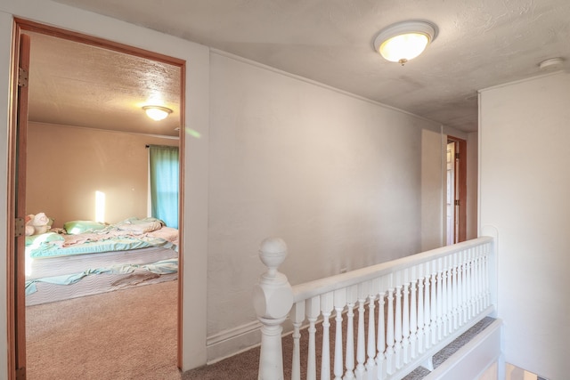 corridor with a textured ceiling and carpet floors