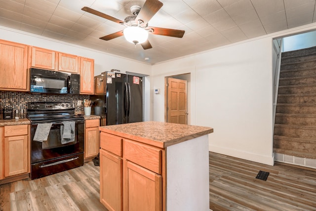 kitchen with crown molding, light hardwood / wood-style flooring, tasteful backsplash, a center island, and black appliances