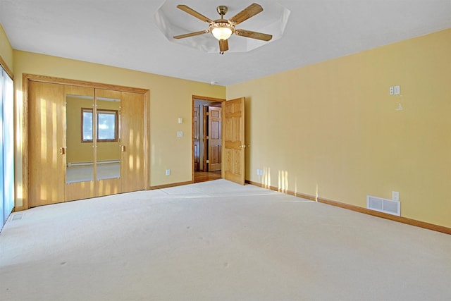 unfurnished bedroom with ceiling fan, light colored carpet, and a closet