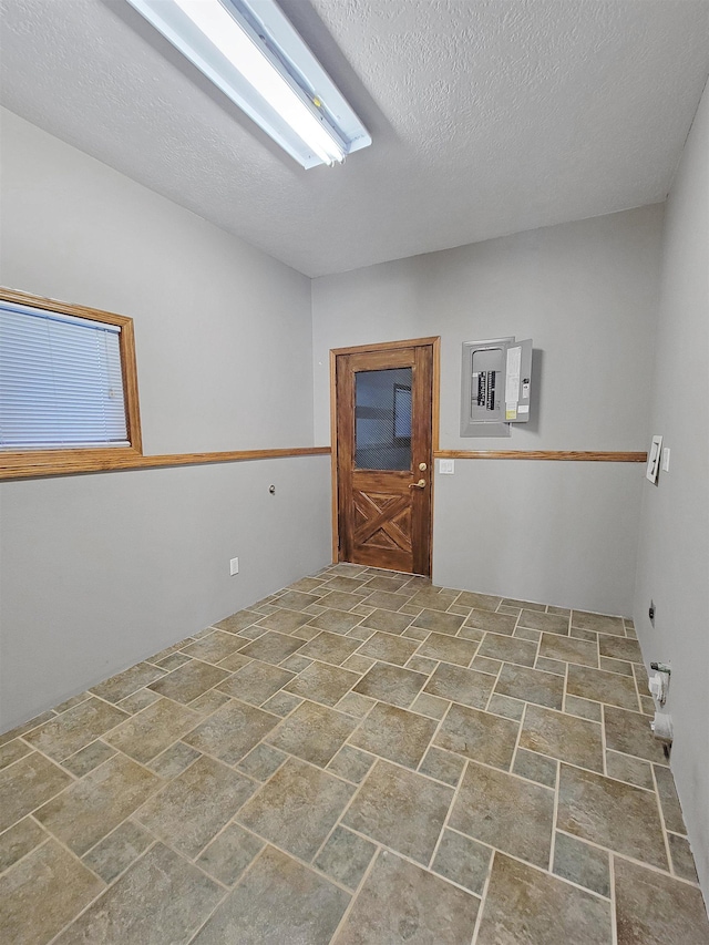 unfurnished room featuring electric panel and a textured ceiling