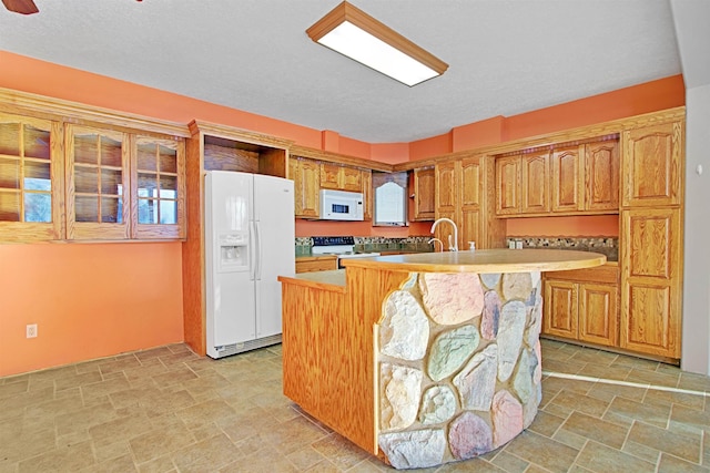 kitchen with white appliances, a center island with sink, and a textured ceiling