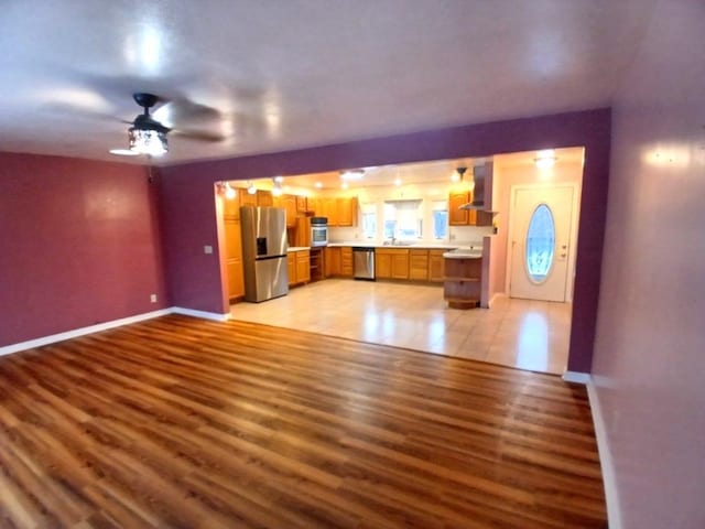 unfurnished living room featuring sink, ceiling fan, and light hardwood / wood-style flooring