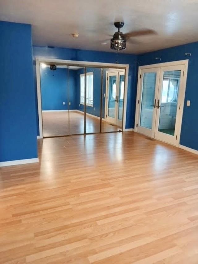 interior space with light wood-type flooring, ceiling fan, and french doors