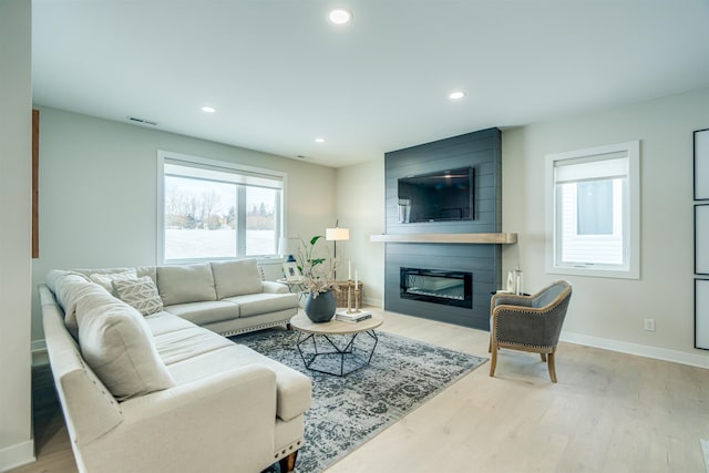 living room with a large fireplace and light hardwood / wood-style floors