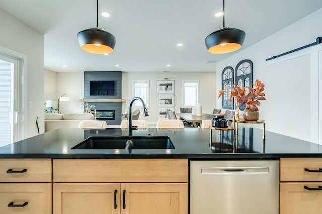 kitchen featuring a barn door, stainless steel dishwasher, decorative light fixtures, and sink