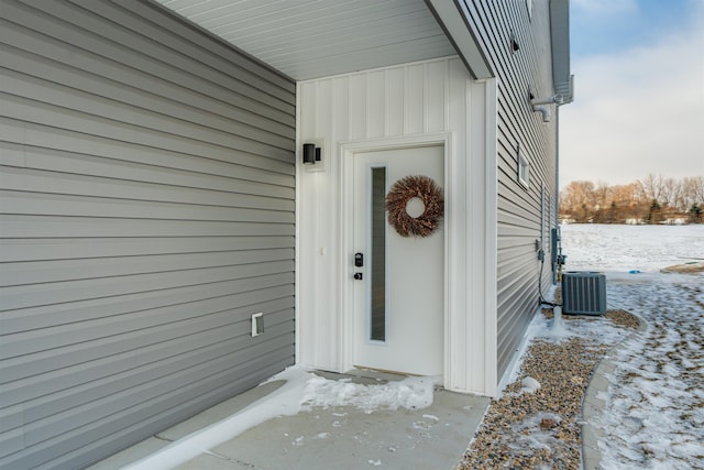 snow covered property entrance with cooling unit