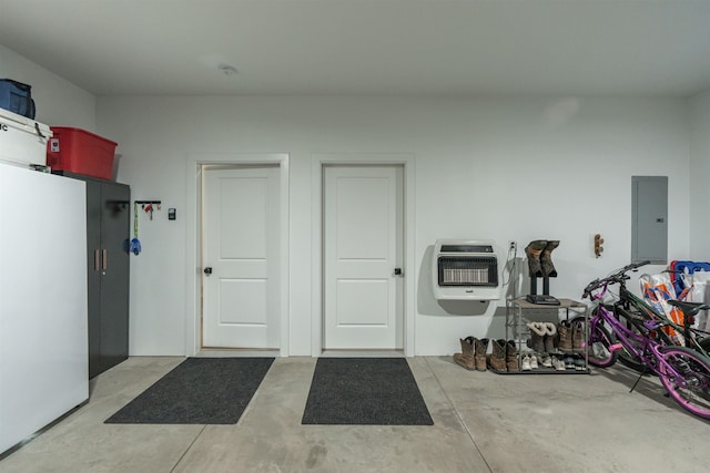 garage with heating unit, electric panel, and white fridge