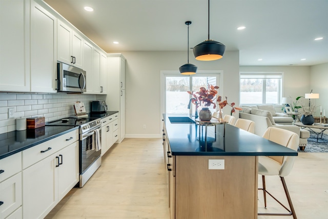 kitchen featuring white cabinetry, sink, a kitchen breakfast bar, hanging light fixtures, and stainless steel appliances