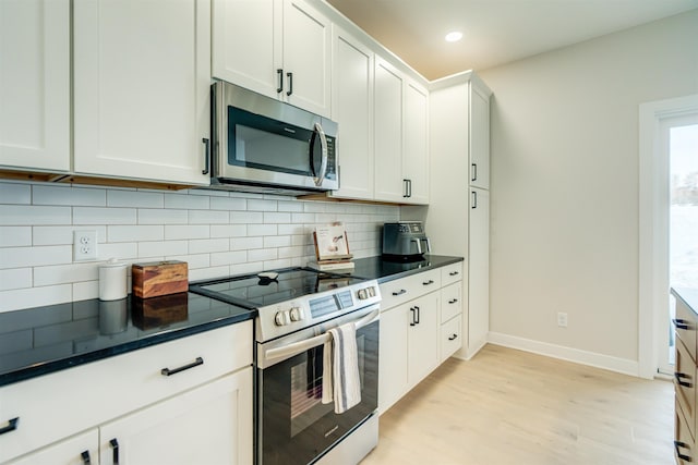 kitchen featuring white cabinetry, decorative backsplash, appliances with stainless steel finishes, and light hardwood / wood-style flooring