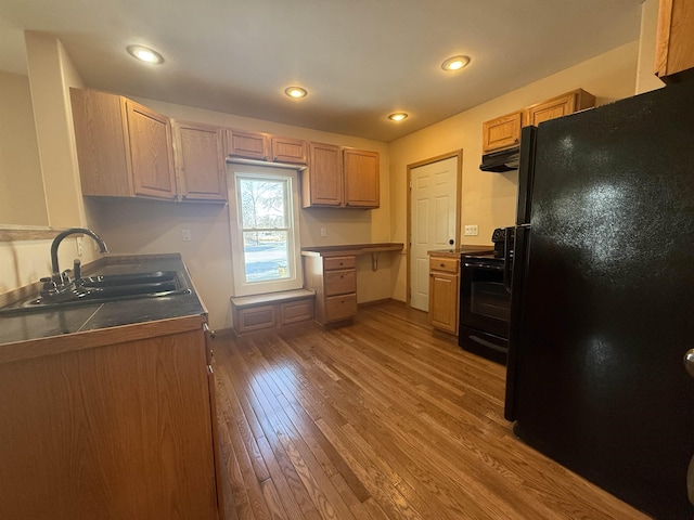 kitchen featuring light wood-type flooring, sink, light brown cabinets, and black appliances