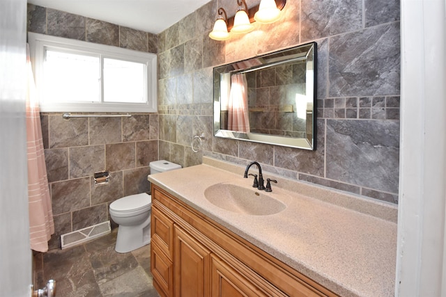 bathroom featuring vanity, tile walls, and toilet