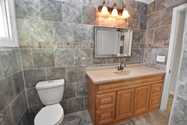 bathroom with vanity, tile walls, and toilet