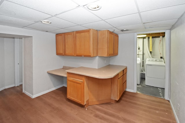 kitchen with a paneled ceiling, washer and clothes dryer, and light wood-type flooring