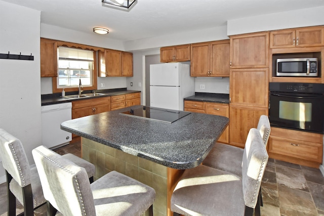 kitchen with a kitchen breakfast bar, sink, a kitchen island, and black appliances