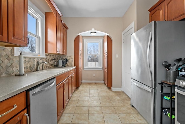 kitchen featuring sink, backsplash, stainless steel appliances, and light tile patterned floors