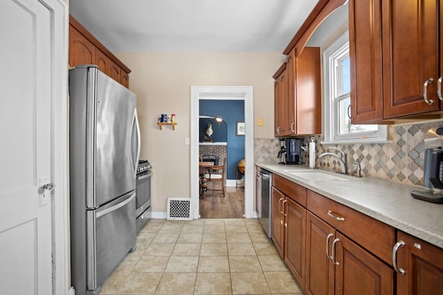 kitchen featuring tasteful backsplash, sink, light tile patterned flooring, and appliances with stainless steel finishes