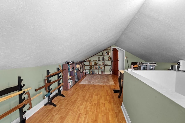 interior space with hardwood / wood-style flooring, lofted ceiling, and a textured ceiling