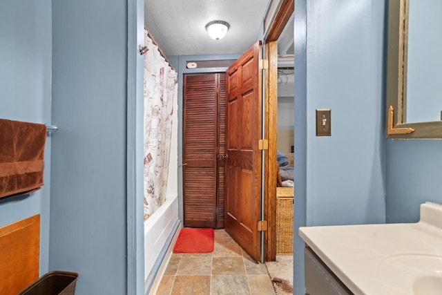 bathroom featuring shower / bath combination with curtain, vanity, and a textured ceiling